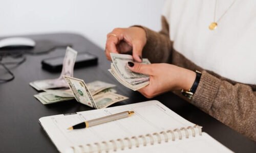 crop-payroll-clerk-counting-money-while-sitting-at-table.jpg